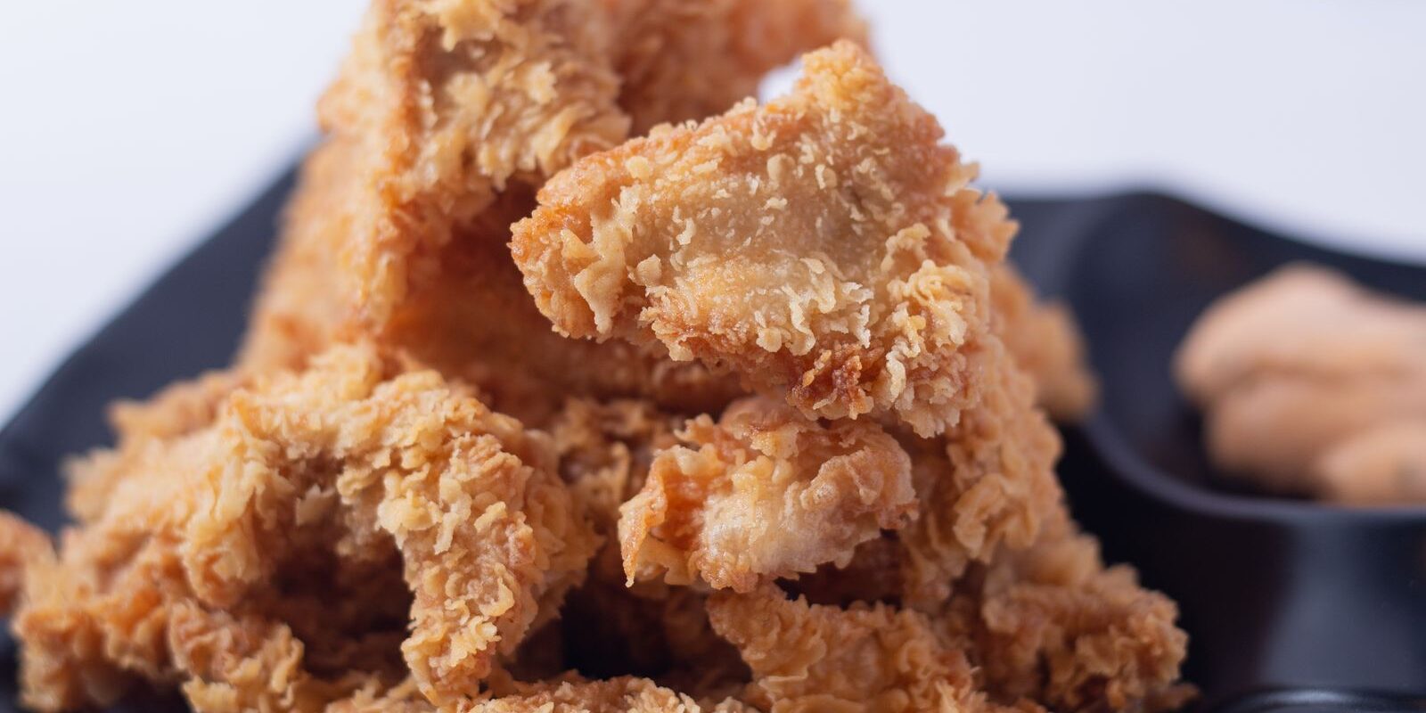 Ayam goreng tepung renyah di atas piring hitam